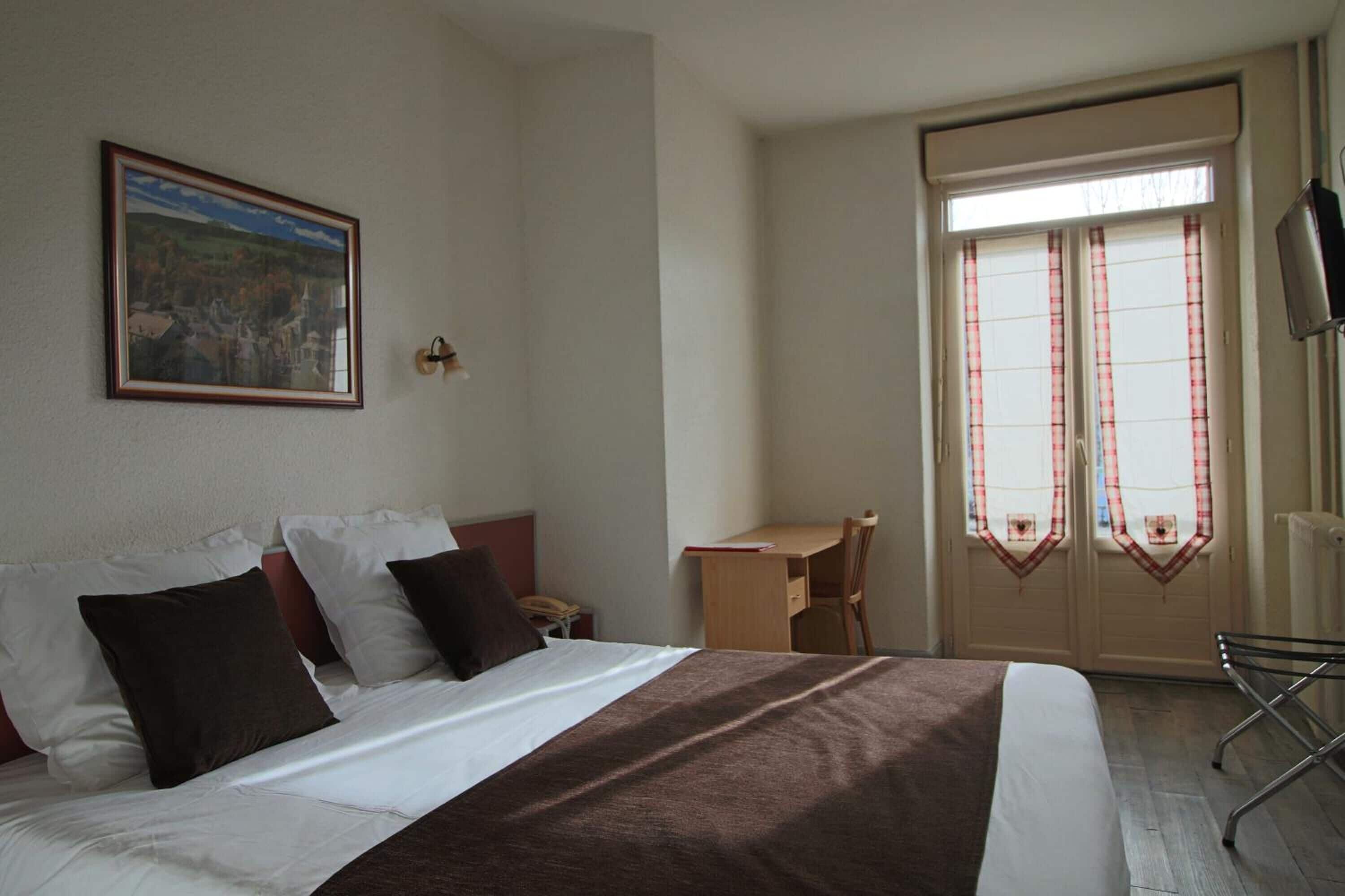 Une chambre d’hôtel avec un lit, un bureau et une chaise.