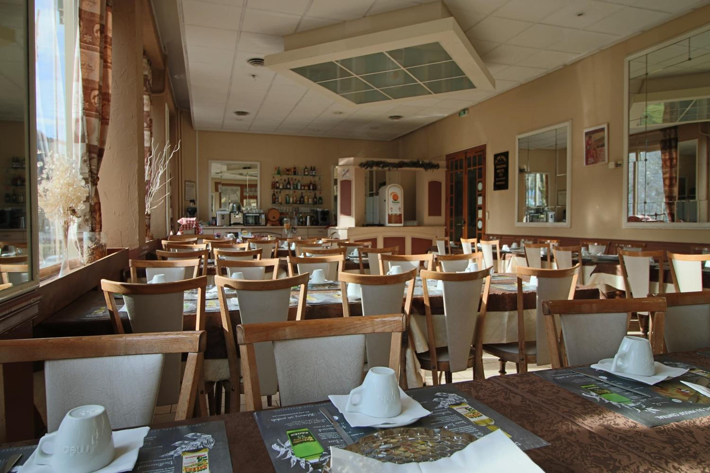 A restaurant with multiple tables and chairs, a bar area, and a counter with a cash register.
