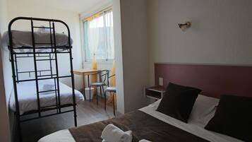 A room with a bunk bed, a single bed, a desk with a chair, and a small table.