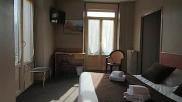 Une chambre d’hôtel avec un lit, un bureau, une chaise et une fenêtre avec des rideaux.
