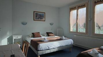 Habitación de hotel con una cama grande, una cama más pequeña, un escritorio y una silla. Hay toallas sobre las camas y un control remoto en el escritorio.