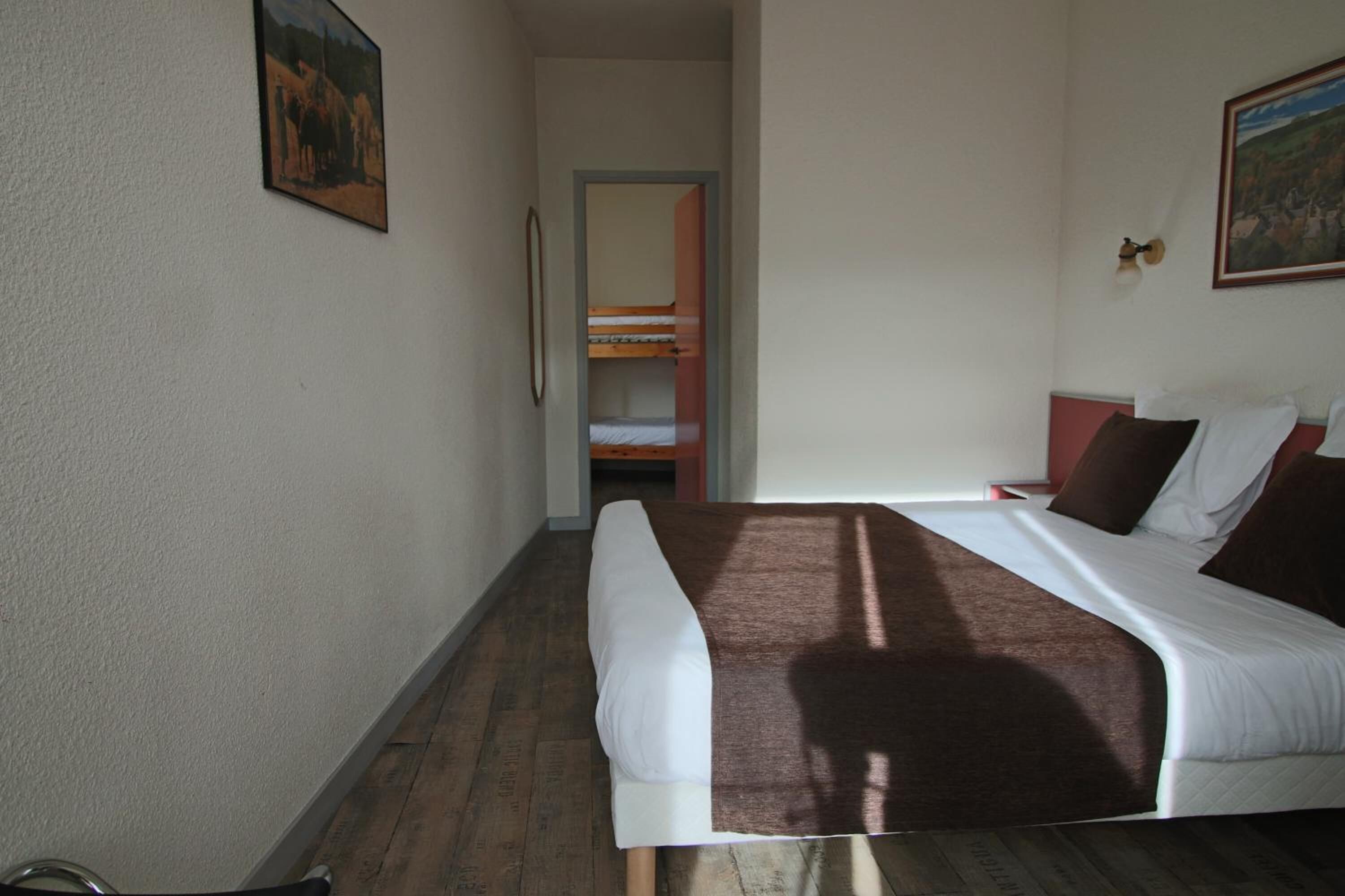 Ein Hotelzimmer mit Bett, Holzboden, einem Bild an der Wand und einer zur Garderobe führenden Tür.