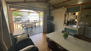 A compact living space with a sofa, dining table, kitchen area, and a view of an RV parked outside. - Camping Arena Blanca (Benidorm)