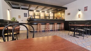 Un restaurante con barra, mesas y taburetes de madera.
