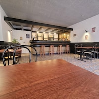 Un restaurante con barra, mesas y taburetes de madera.
