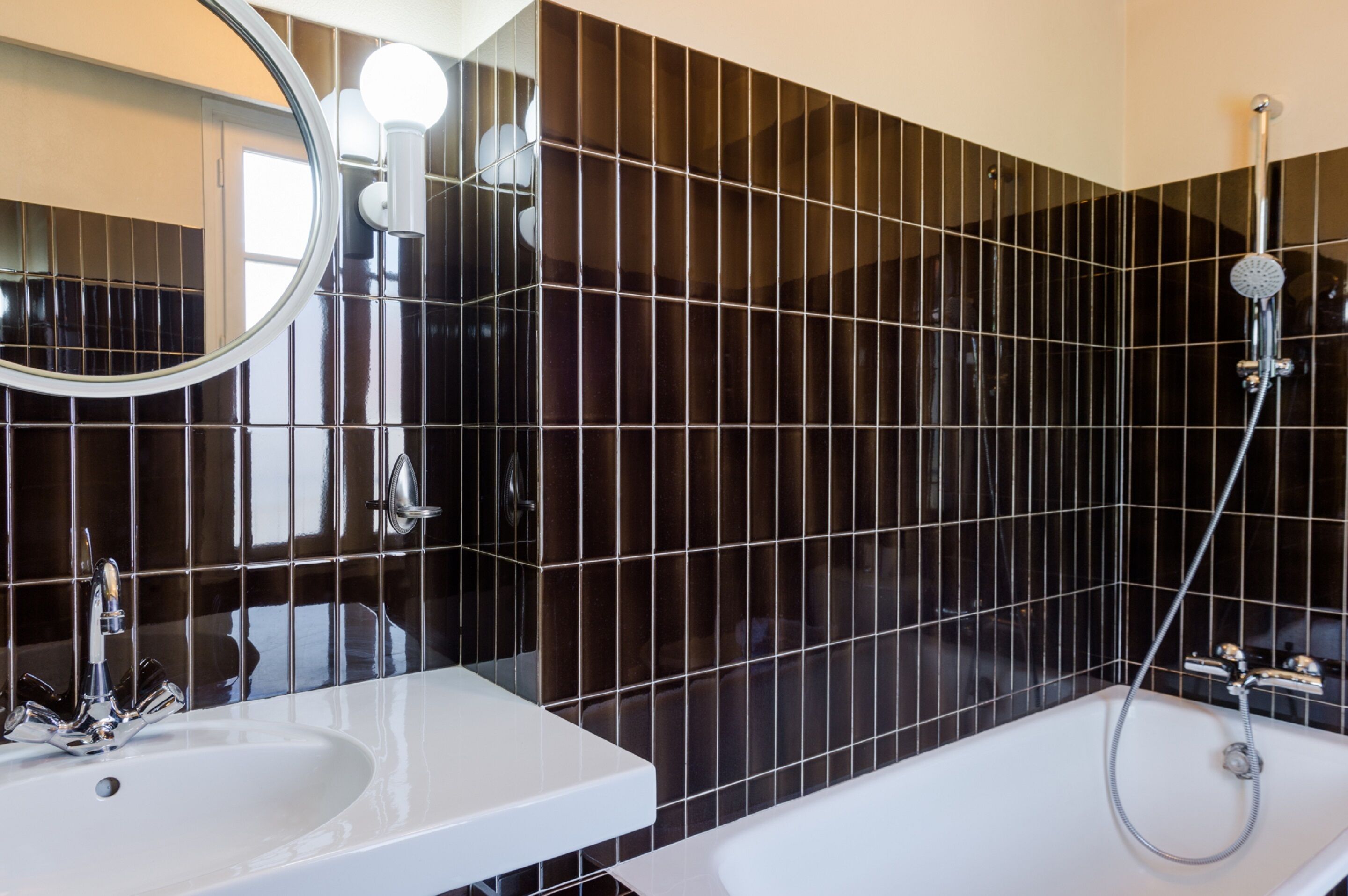Un baño moderno con un espejo grande, un lavamanos y una bañera.