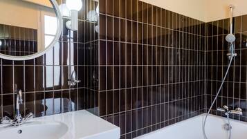 Un baño moderno con un espejo grande, un lavamanos y una bañera.