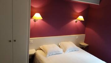 Une chambre d’hôtel avec un lit, deux lampes de chevet et un mur agrémenté d’une touche de couleur rouge.
