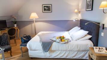 Une chambre d’hôtel bien rangée, avec un lit, une table de chevet, une lampe, une chaise et un petit bureau avec un ordinateur portable.
