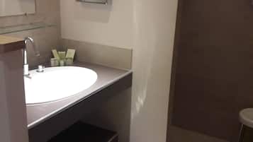 A modern bathroom with a white sink, a mirror, and a trash bin.