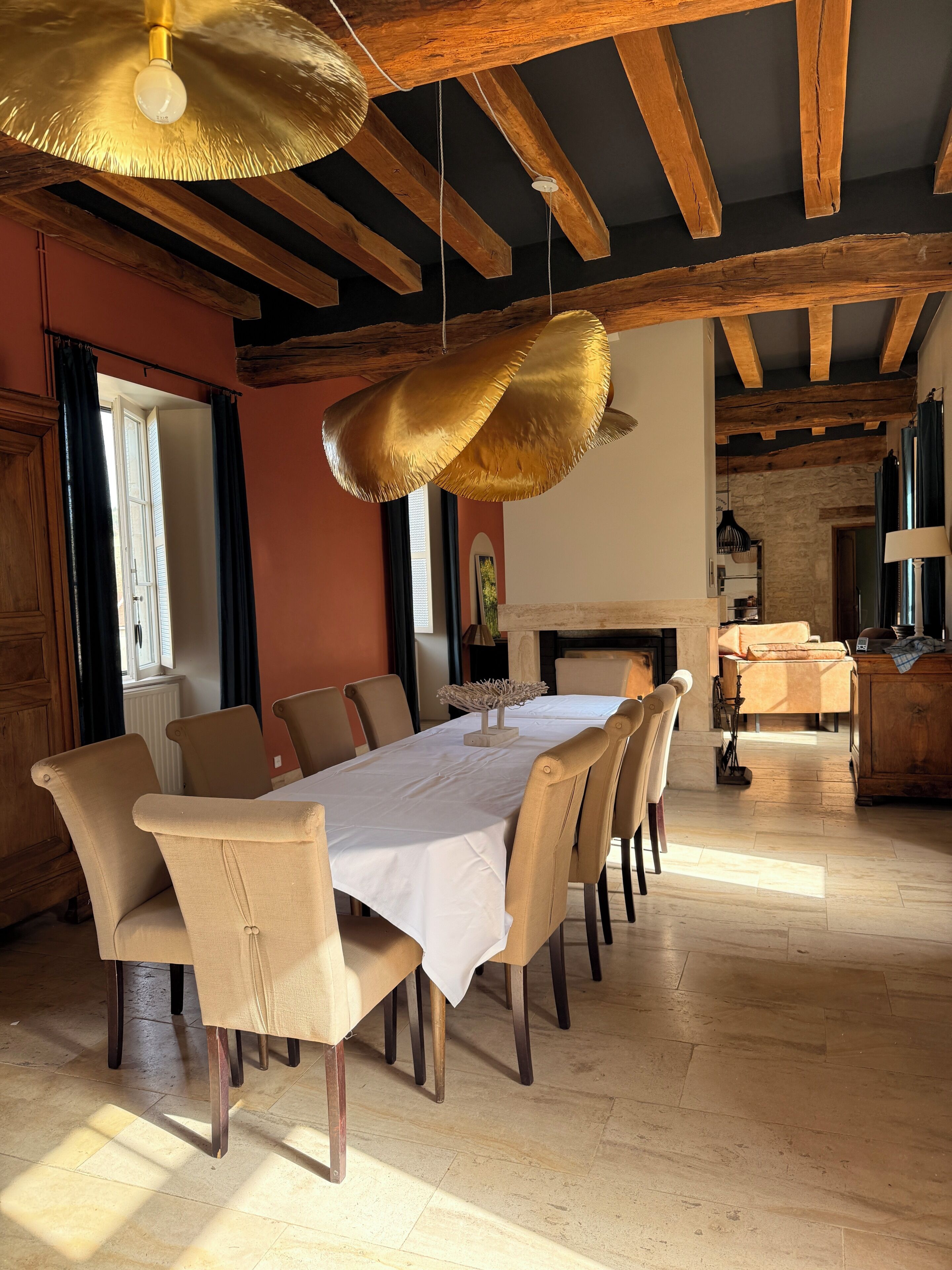 A dining area with a long table, chairs, and hanging pendant lights.