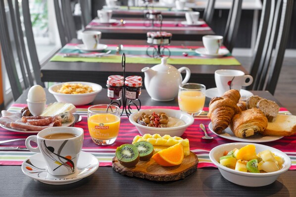 Un buffet de petit-déjeuner proposant une variété d'aliments, notamment des fruits, des viennoiseries et des boissons.