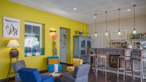 Una sala moderna con una pared de acento amarilla, una zona de bar con taburetes y una mesa de comedor.