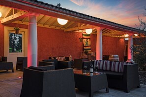 Un patio al aire libre con muebles de mimbre, una botella de vino y una bandera.