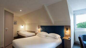 A hotel room with two beds, a window with a view, and a small table with a chair.
