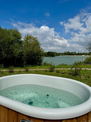 A hot tub with a clear view of a lake and trees in the background. - Eden Park Hotel Restaurant (Pont-l'Eveque)