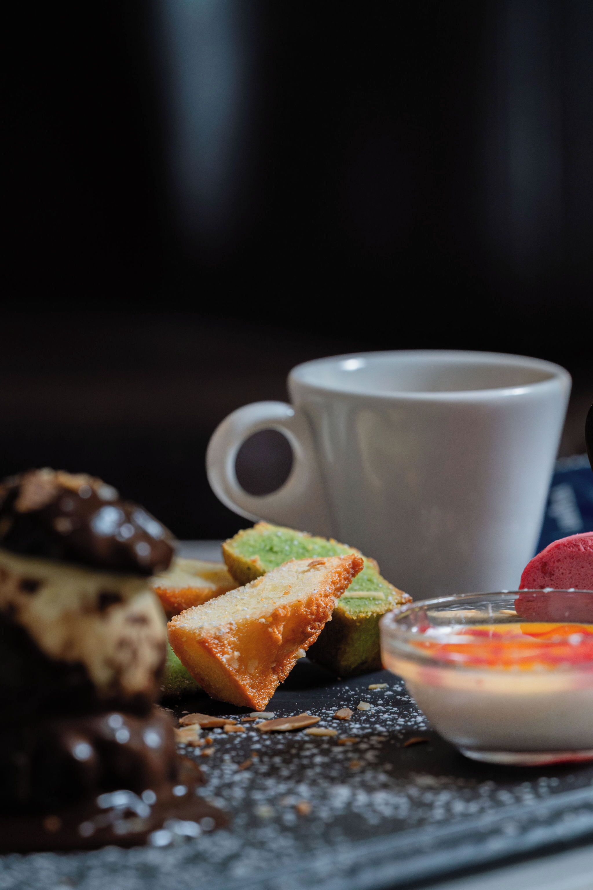 Une assiette à dessert avec divers types de sucreries et une tasse blanche.