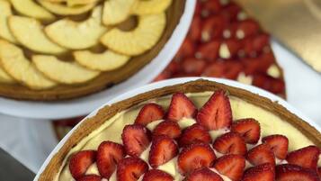 A dessert display with a tart topped with sliced strawberries and another with apple slices.