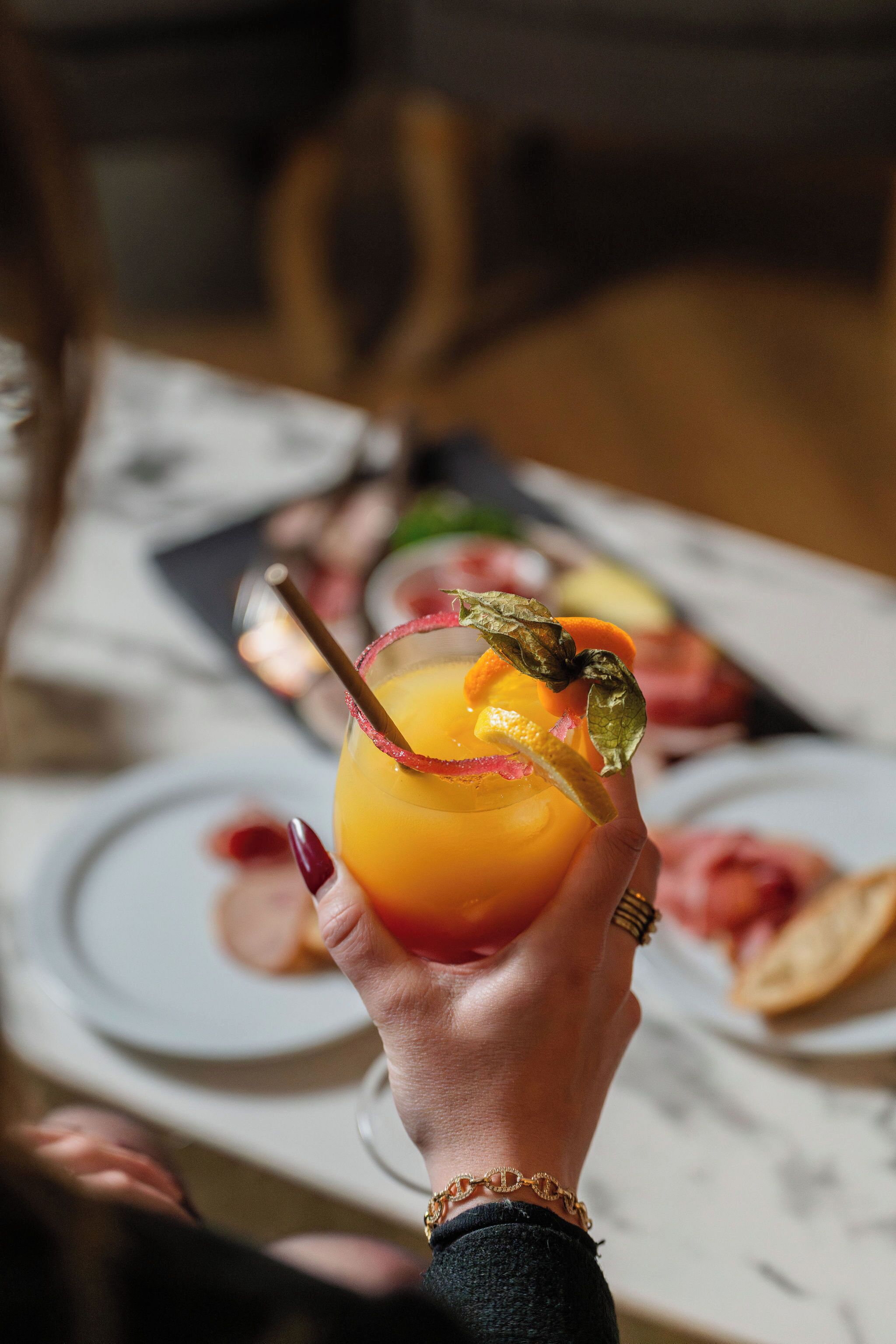 A hand holding a cocktail with a lemon twist garnish.