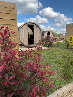 A wooden cabin with a circular door, surrounded by a grassy area with shrubs and a clear sky. -  Eden Park Hotel Restaurant (Pont-l'Eveque)