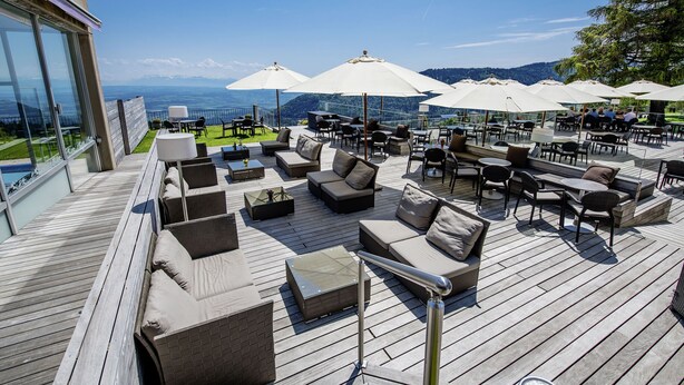 Une terrasse avec des espaces de détente en plein air, comprenant des canapés et des tables, ainsi que des parasols pour créer de l’ombre.