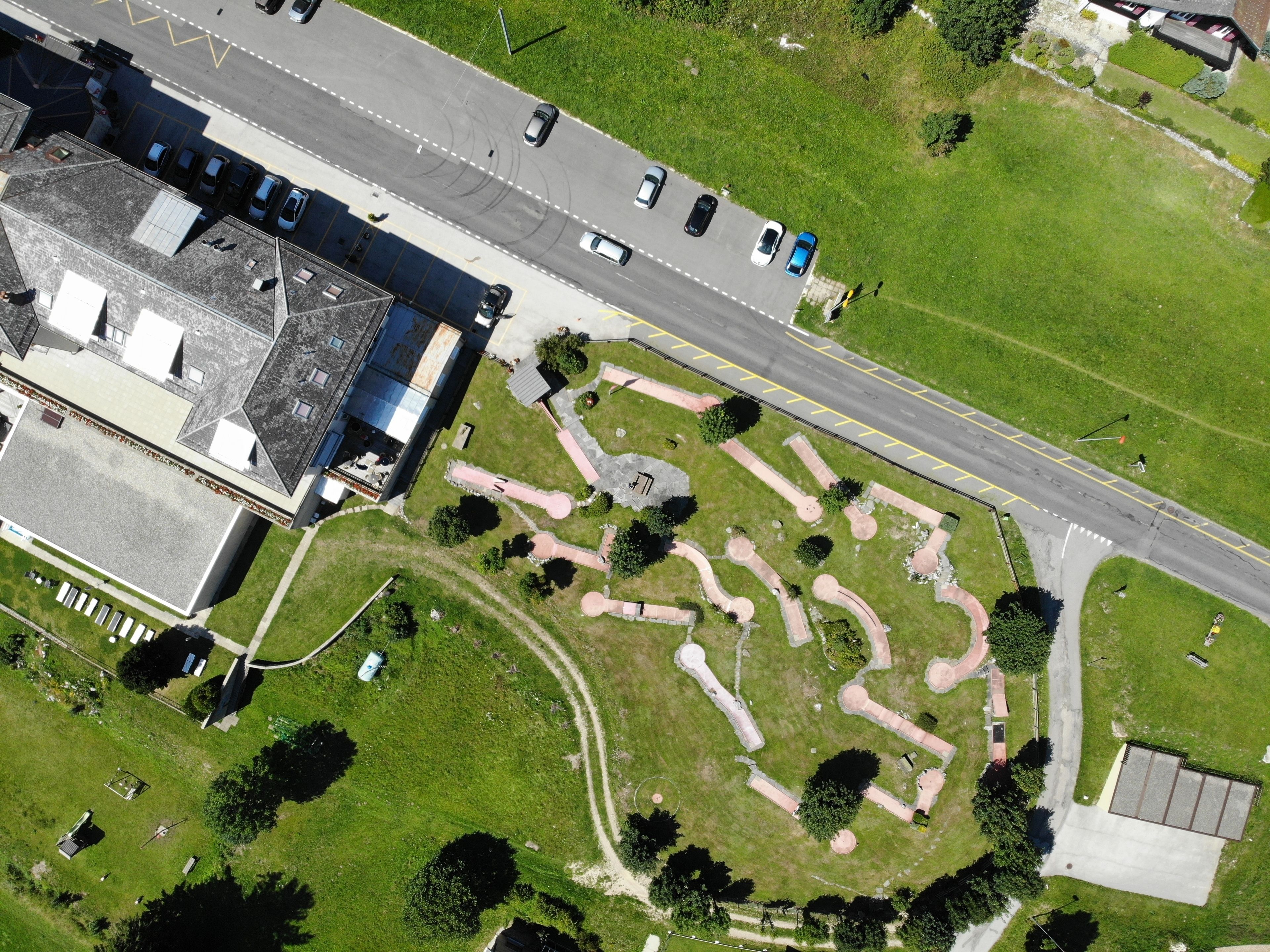 Ein Gebäude aus der Vogelperspektive mit Parkplatz und begrüntem Gartenbereich.