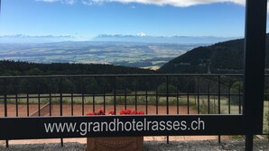 Une enseigne pour le Grand Hôtel des Rasses, offrant une vue panoramique sur les montagnes et les champs.