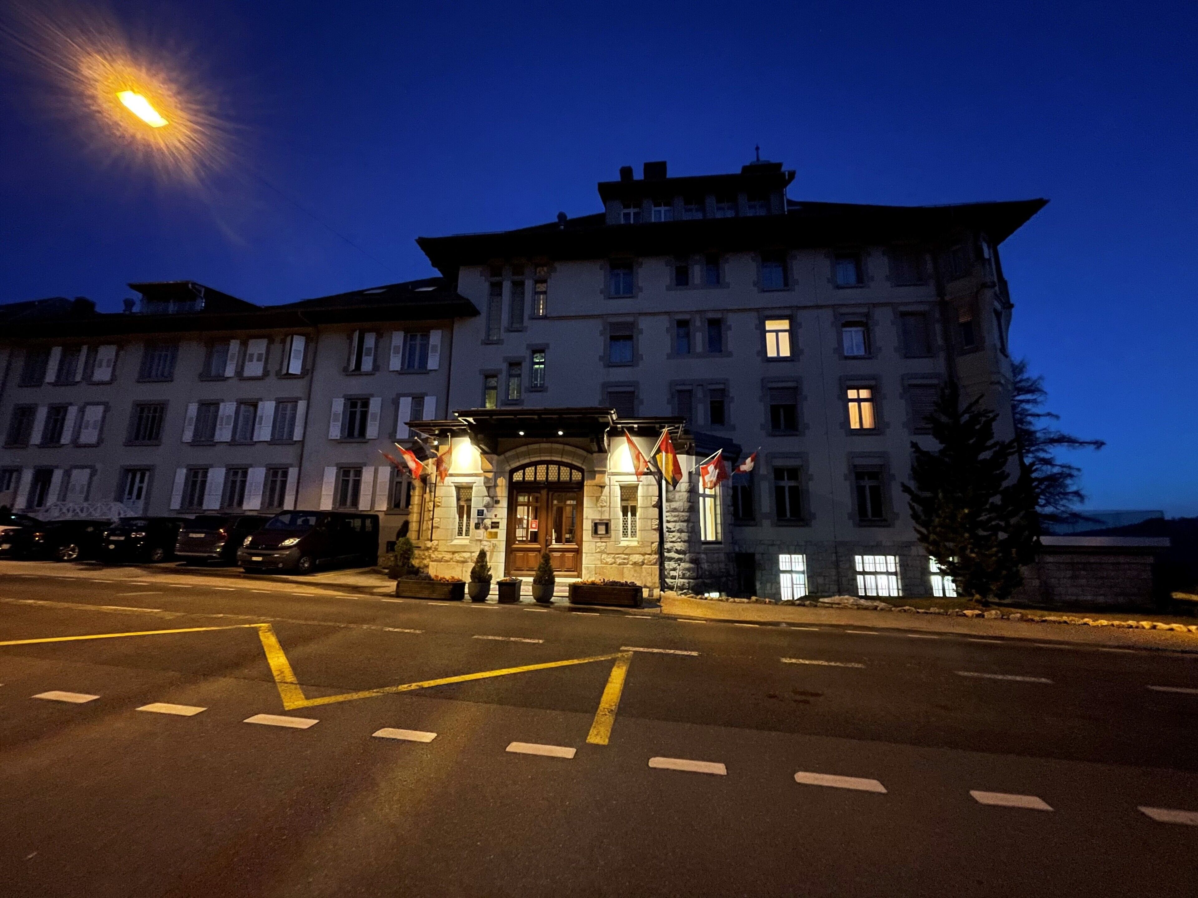 A multi-story hotel with a prominent entrance and a parking area in front.