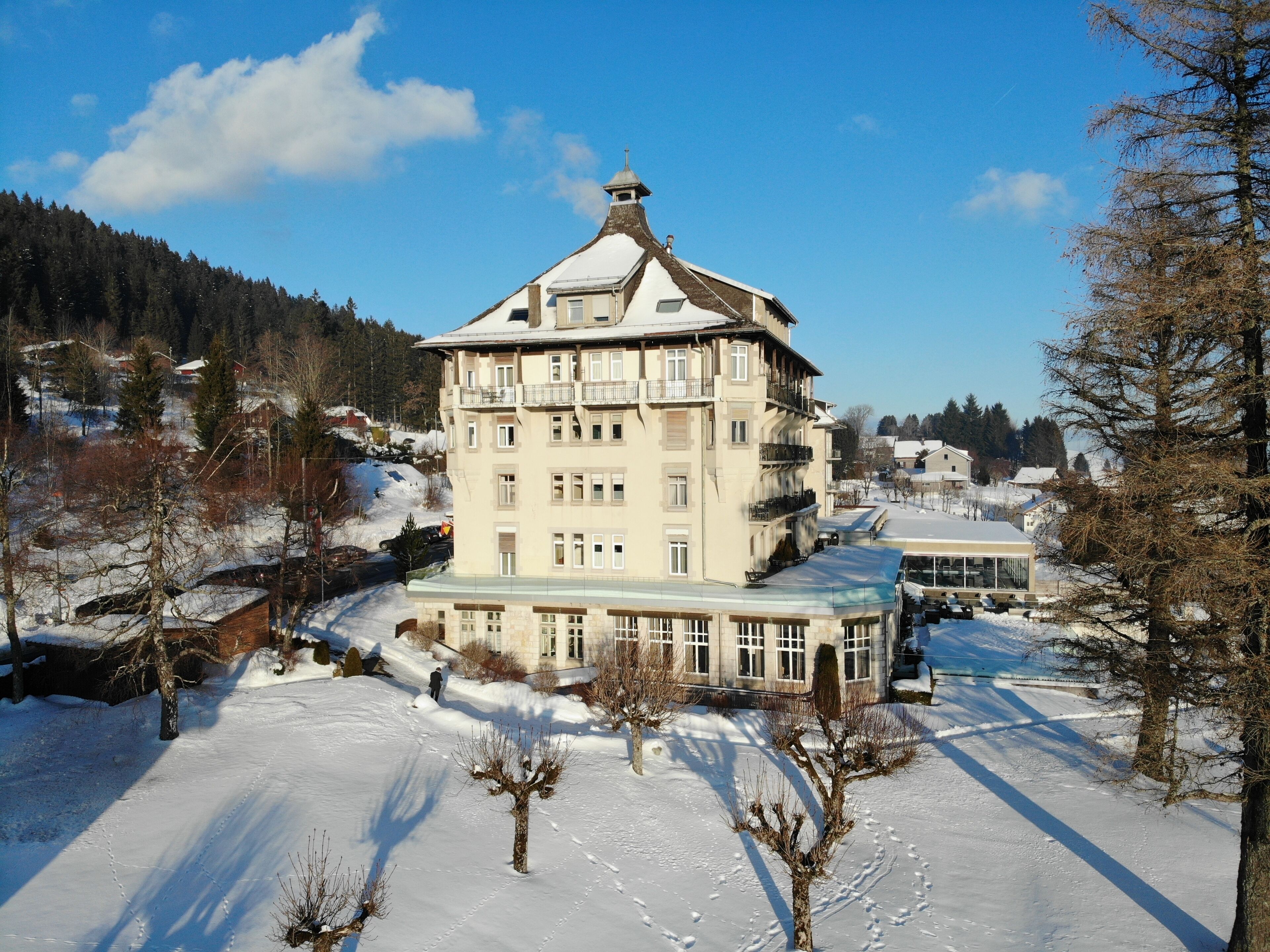 A multi-story building with a snow-covered roof and a balcony on the upper floor.