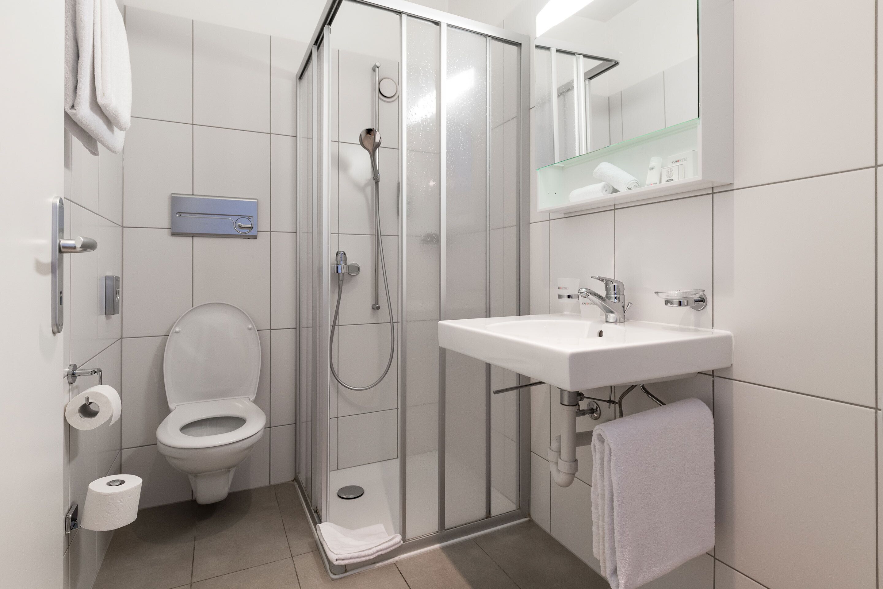 A modern bathroom with a toilet, shower, and sink.