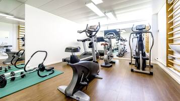 Une salle de sport équipée de divers appareils d’exercice, notamment des tapis de course, des appareils elliptiques et des machines de musculation.