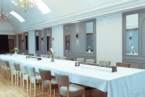 A conference room with a long table, chairs, and a chandelier.