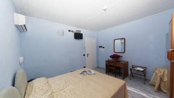 Una habitación con cama, escritorio, silla, espejo y puerta.