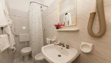 Une salle de bain équipée de toilettes, d’un lavabo et d’un rideau de douche.