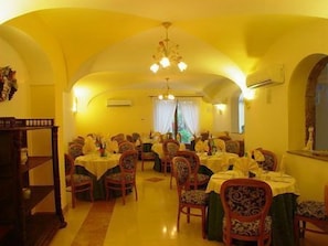 A dining area with multiple tables and chairs, an arched ceiling, and a chandelier. - Hotel Villa Franca (Forio)