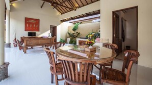 Un espace repas comprenant une table ronde en verre, des chaises en bois et un arrangement floral central.
