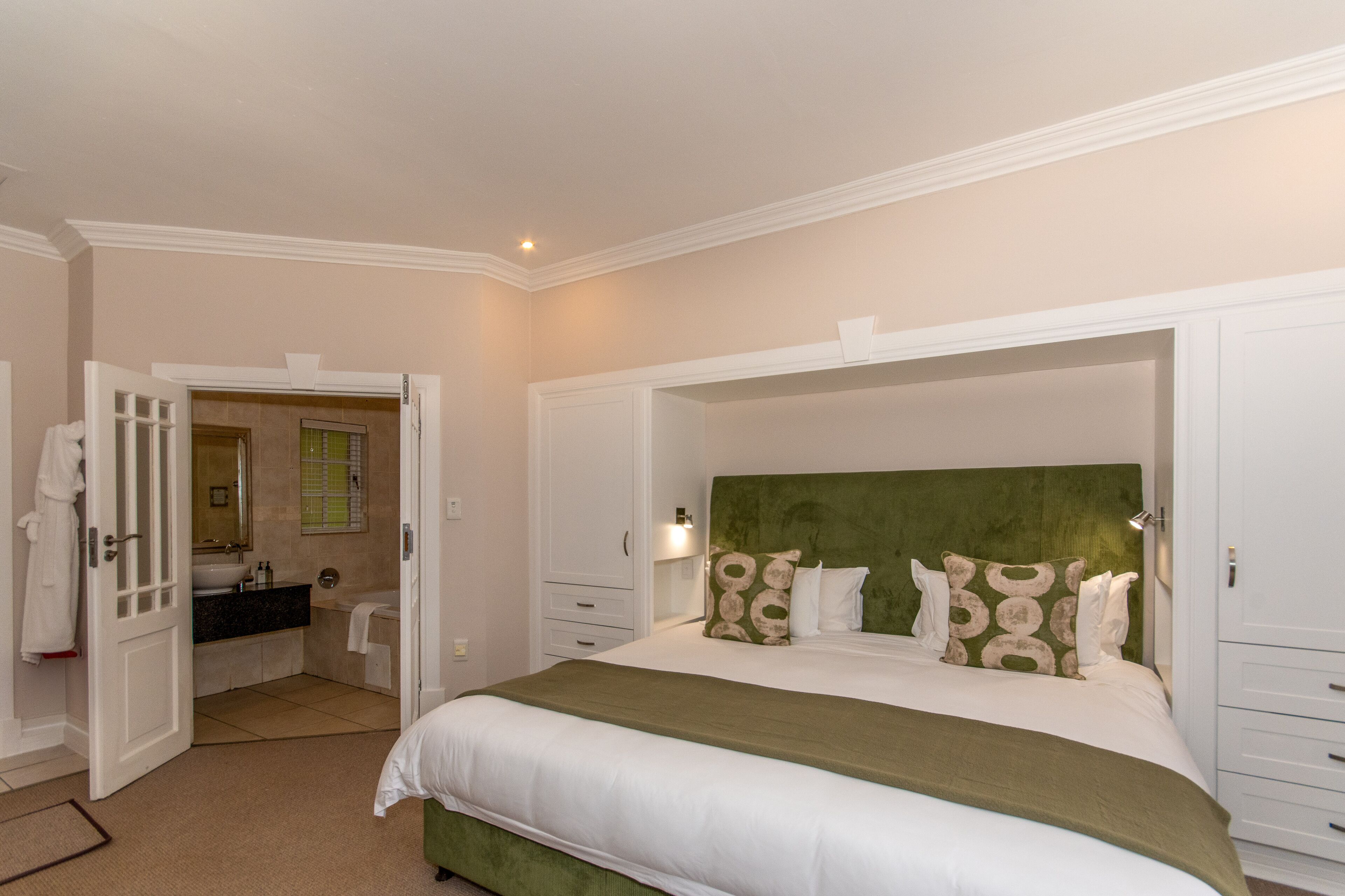A bedroom with a large bed, a green headboard, and a white dresser.