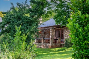 A stone building with a metal roof, surrounded by lush greenery. - Walkersons Hotel & Spa (Dullstroom)