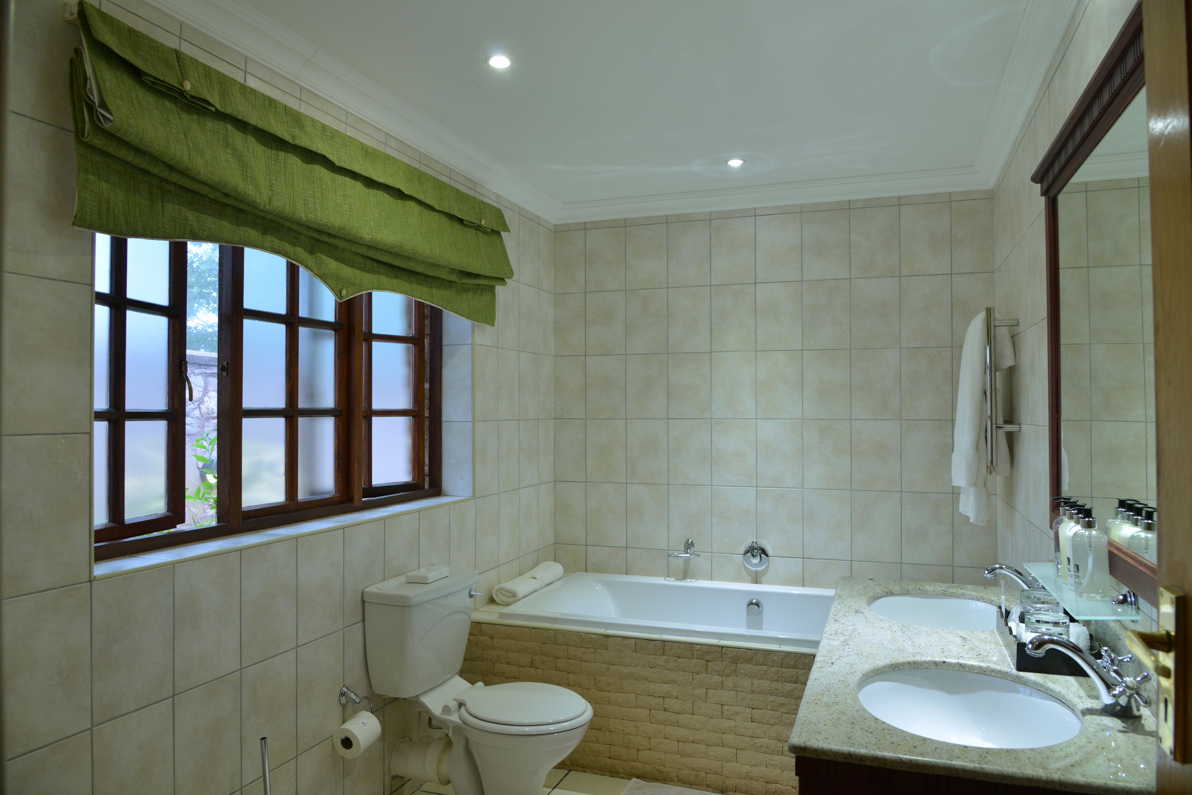 A bathroom with a toilet, a bathtub, and two sinks.
