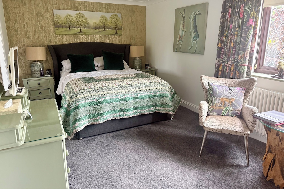 Une chambre à coucher avec un lit, une chaise, un bureau, une lampe et un tableau au mur.