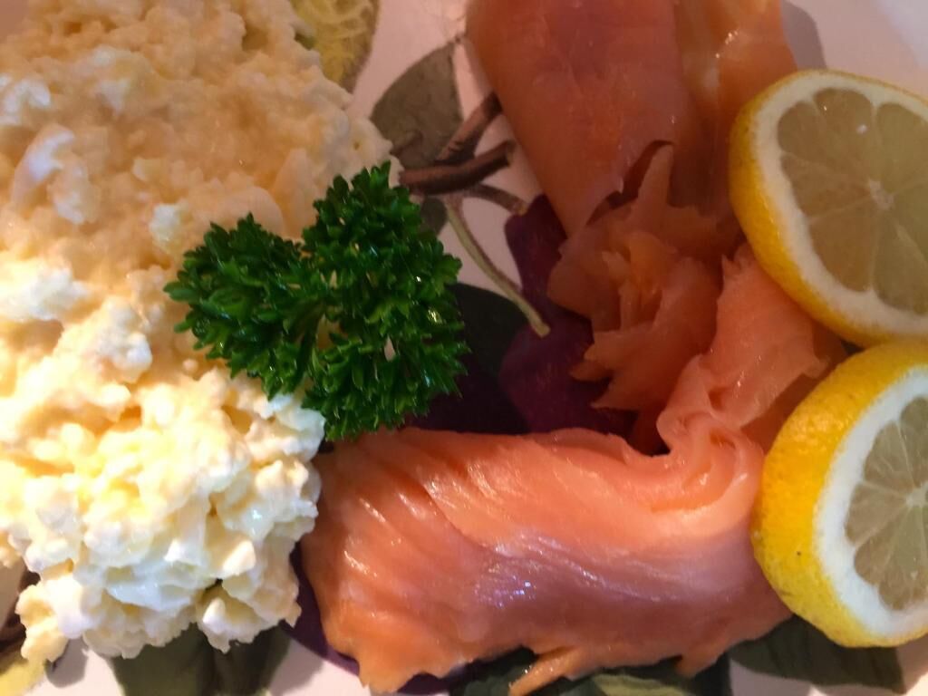 Un plat amb ous barrejats, salmó fumat, una guarnició de julivert i una làmina de llimona.