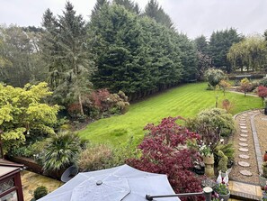 A well-maintained garden with a variety of trees and shrubs, a neatly trimmed lawn, and a stone pathway. - Beechwood B&B (Lewes)