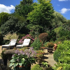 A garden with a pathway, potted plants, and two lounge chairs. - Beechwood B&B (Lewes)
