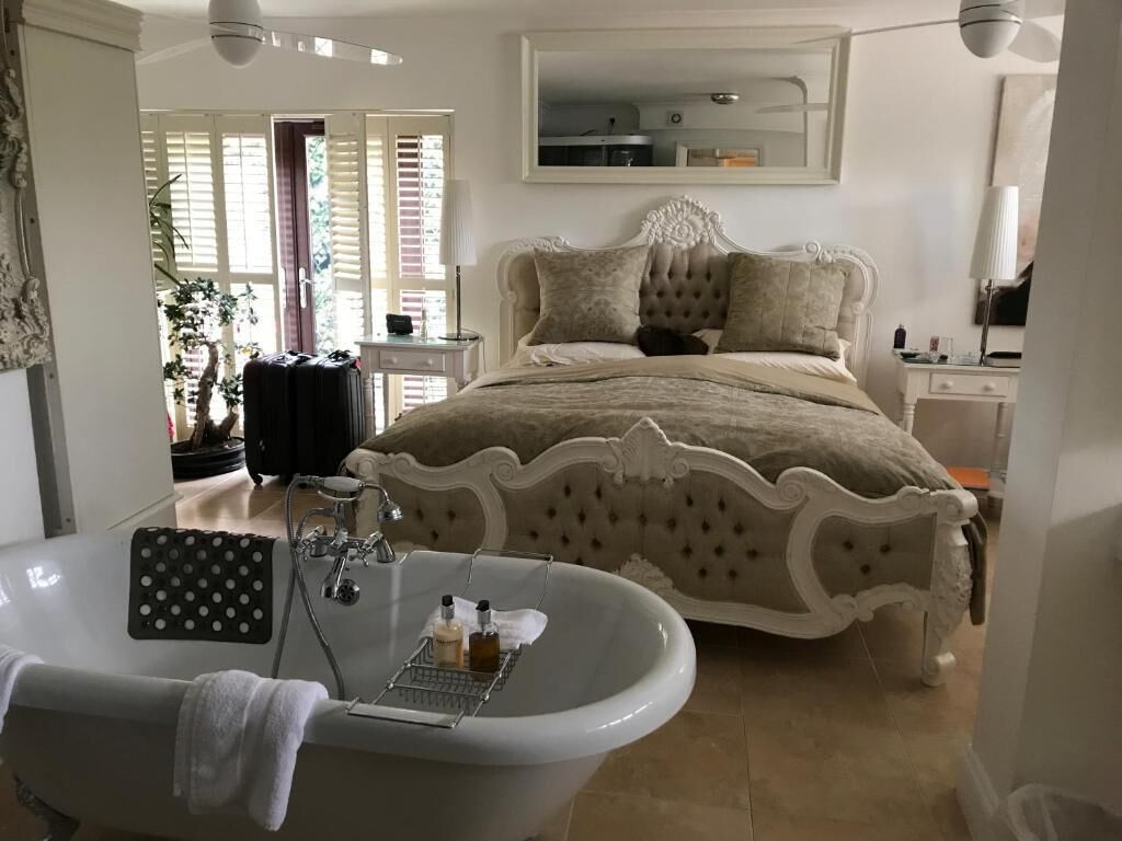 Un dormitorio con una cama grande, una bañera y un espejo sobre la cama.