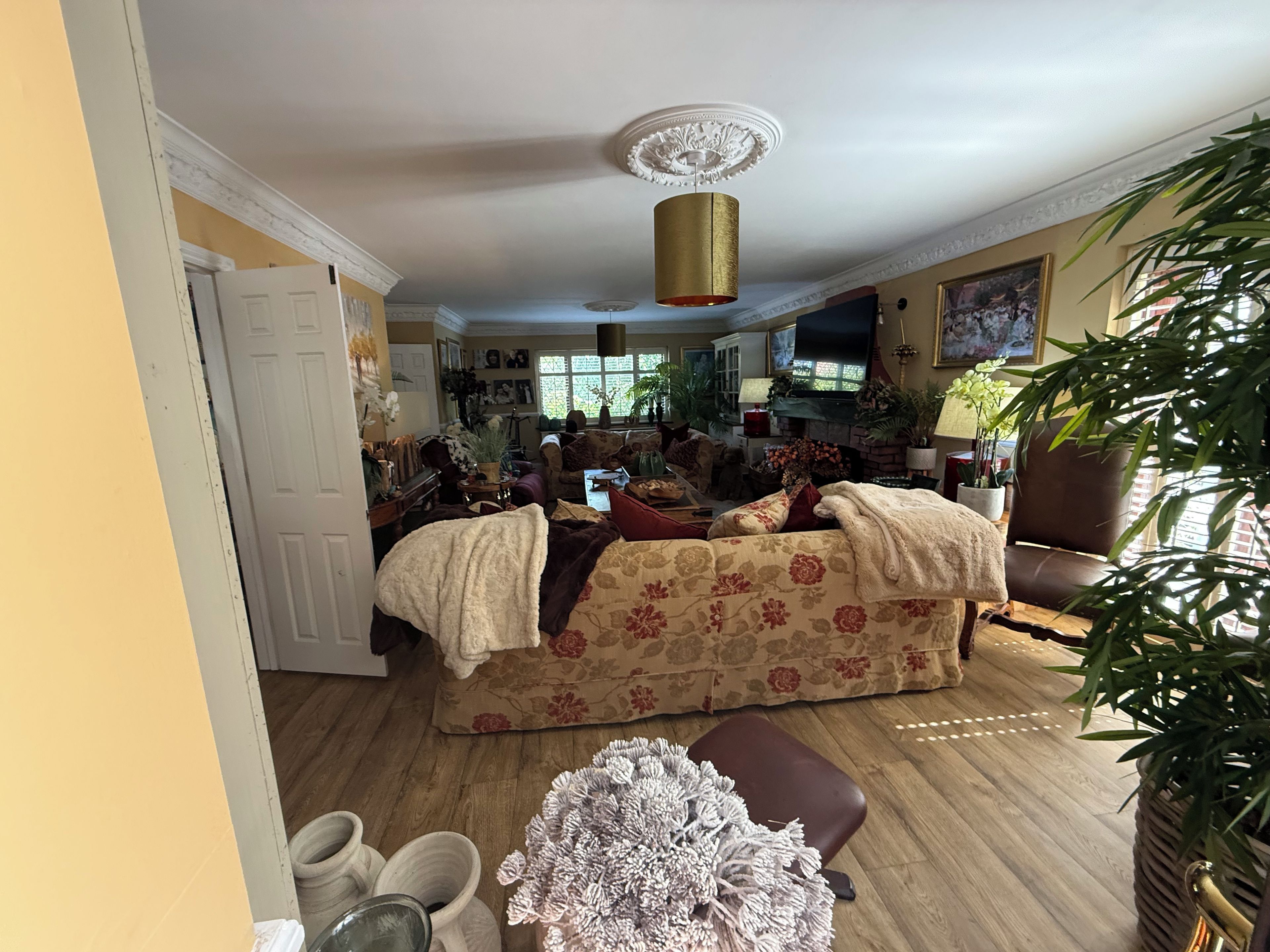 Ein Wohnzimmer mit einer Couch, einem Couchtisch und einem Kamin. Üchtis und ein Fernseher sind ebenfalls vorhanden.