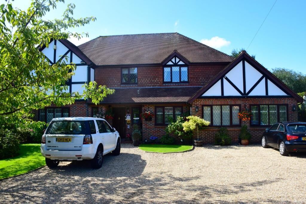 A two-story house with a gravel driveway and a car parked in front.