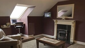 A living room with a fireplace, a sofa, a television, and a skylight. - Causeway Lodge (Bushmills)