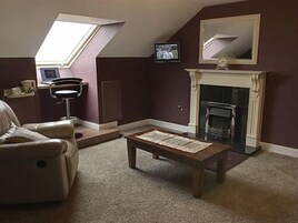 Una sala de estar con chimenea, un sofá, un televisor y un tragaluz.