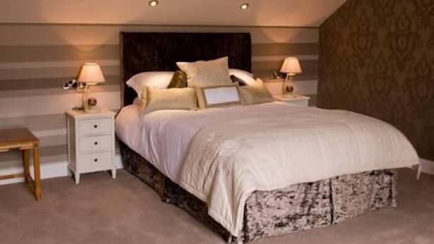 A bedroom with a bed, two bedside tables, and a nightstand. - Causeway Lodge (Bushmills)