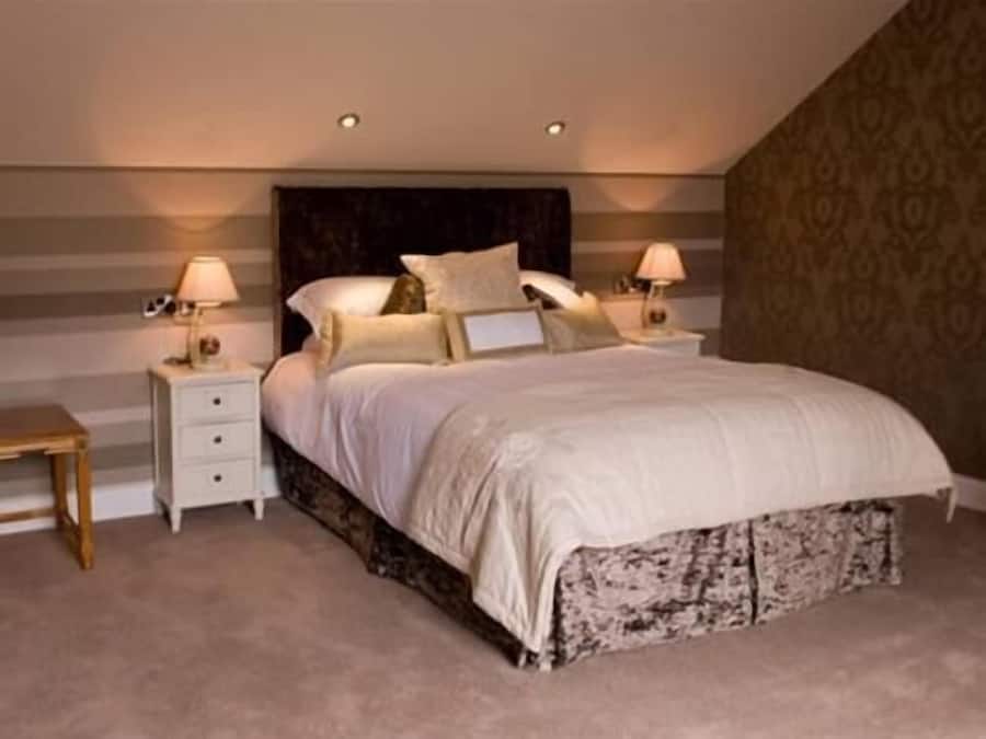 Une chambre à coucher avec un lit, deux tables de chevet et une petite table d’appoint.